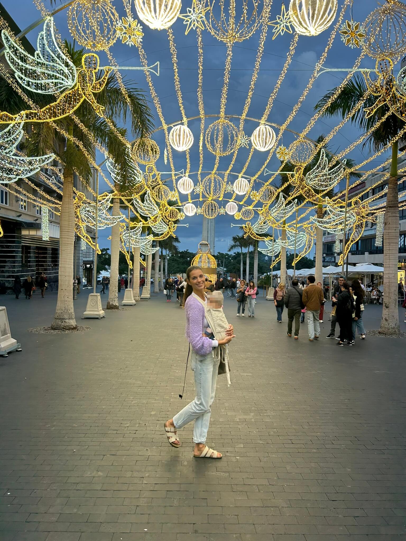 Mama mit Baby in der Trage im weihnachtlich geschmückten Santa Cruz de Teneriffa